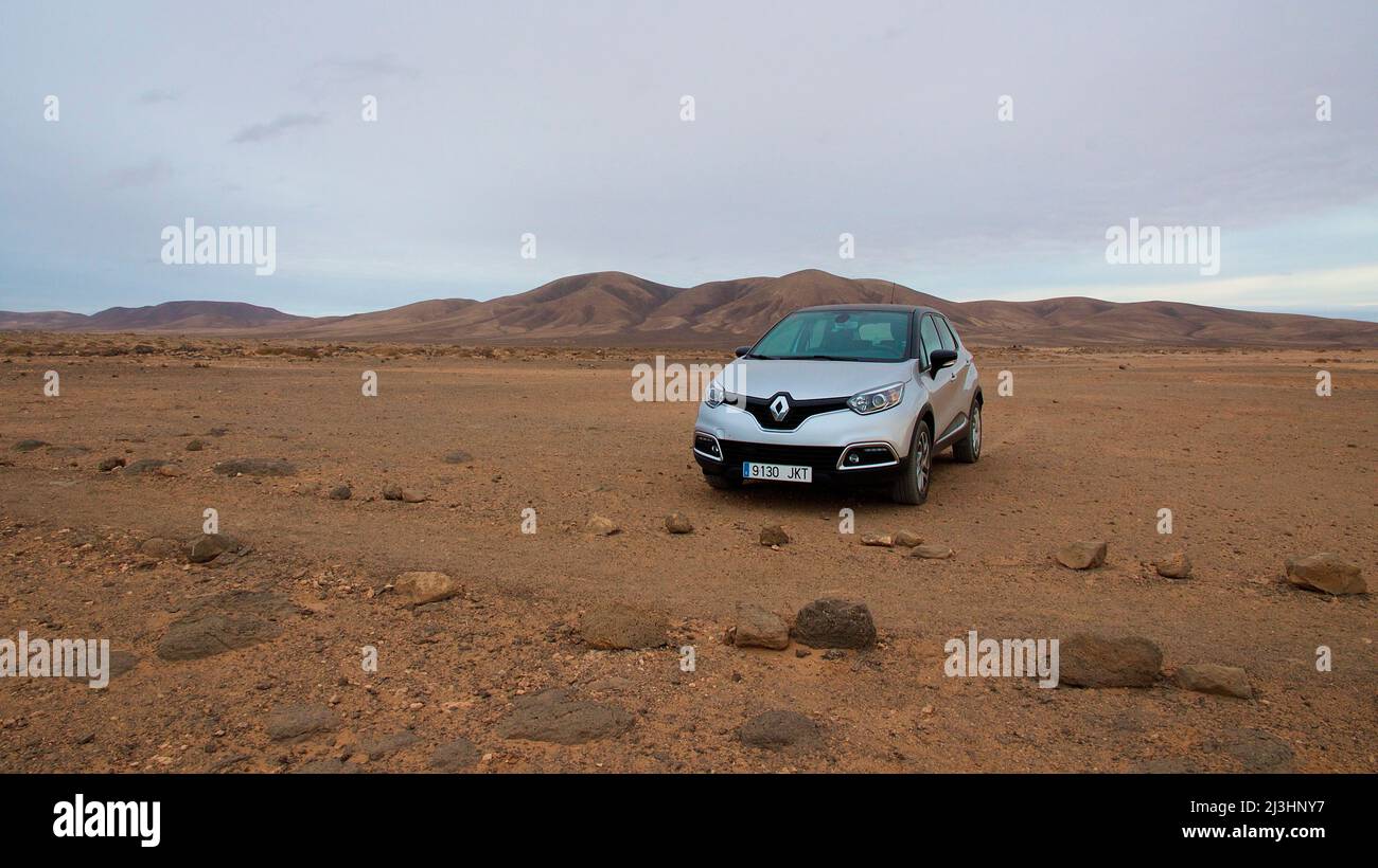 Spagna, Isole Canarie, Fuerteventura, costa occidentale, Playa del Aguila, paesaggio costiero arido, auto a noleggio parcheggiata in argento, cielo coperto e grigio Foto Stock