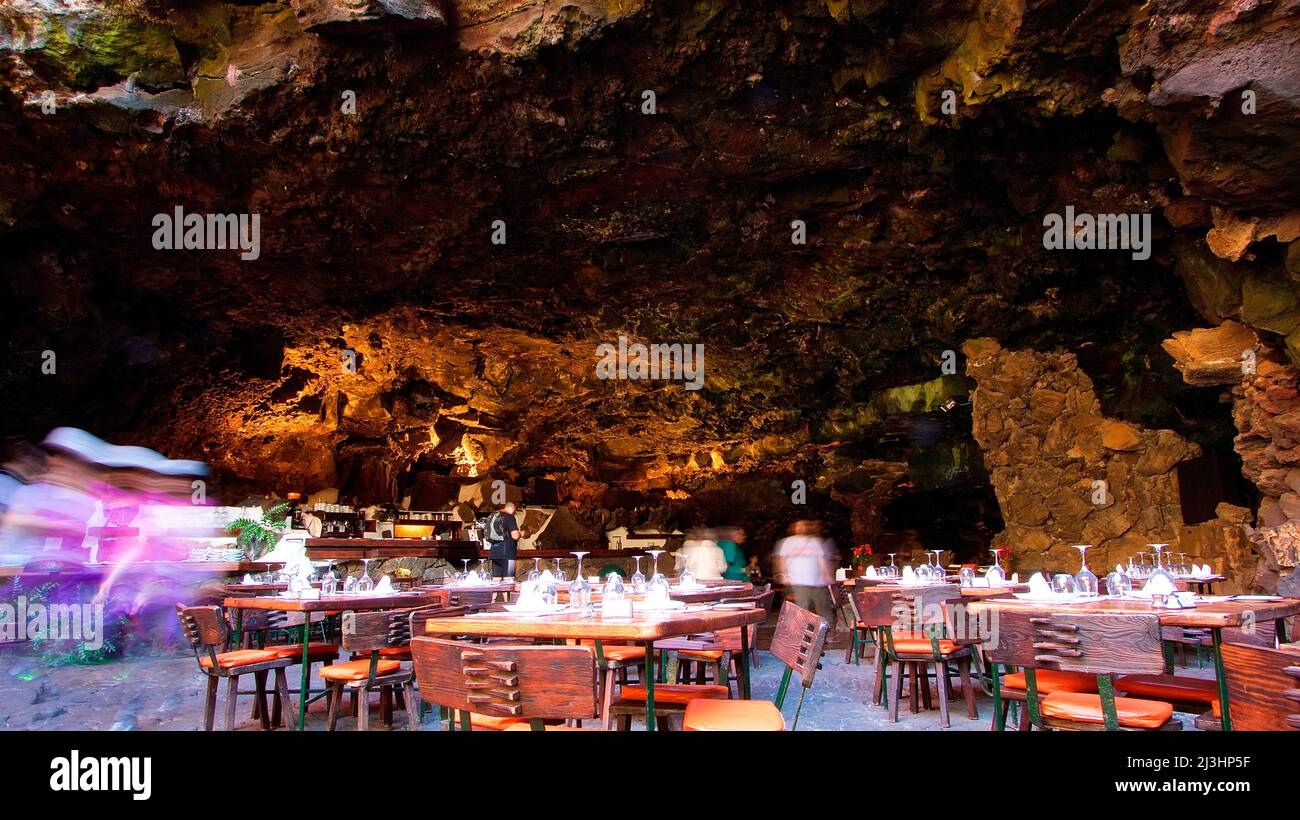 Isole Canarie, Lanzarote, isola vulcanica, Jameos del Agua, progettato da Cesar Manrique, unico tunnel vulcanico e grotte con sala da concerto sotterranea, ristorante e lago salato, ristorante all'interno di grotta di lava, esposizione a lungo termine, persone sfocate Foto Stock