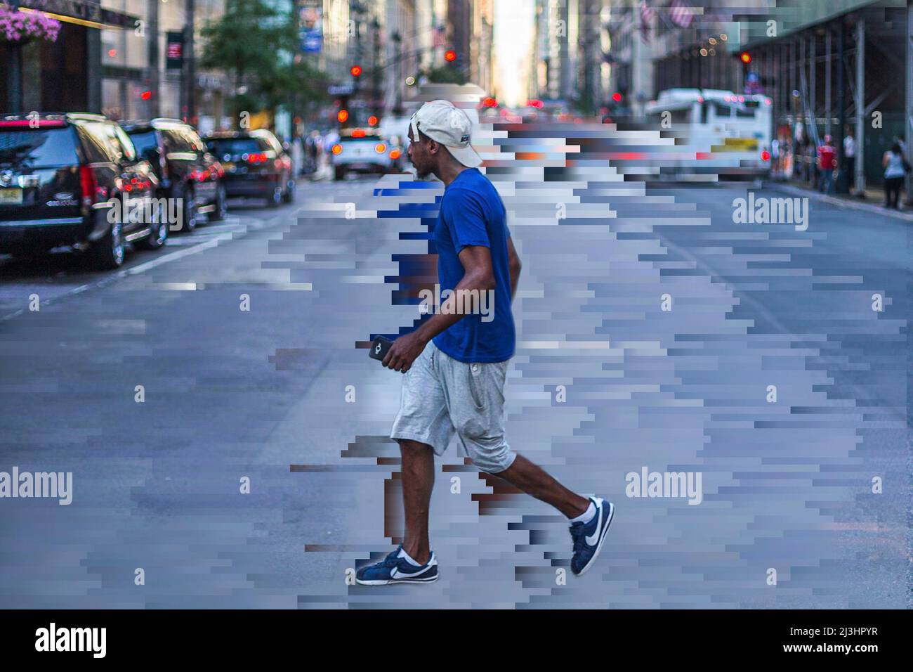 Madison Av/e 41 Street, New York City, NY, USA, Un ragazzo nero con una t-shirt blu e un cappellino da baseball che tiene il suo cellulare attraversando la strada Foto Stock