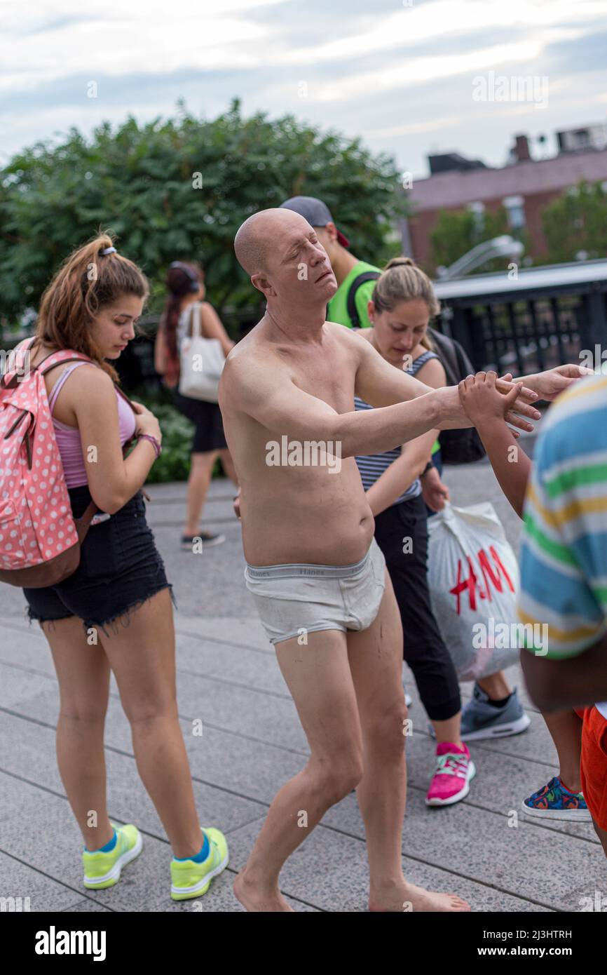 Chelsea, New York City, NY, USA, Mostra 'Wanderlust' all'High Line (un popolare parco lineare costruito sulle piste dei treni sopraelevati sopra la Tenth Ave). In Focus, lo "Sleepwalker" di Tony Matelli, una scultura iperreale di un vecchio che si agguanta nelle sue sagguardee bianche. Foto Stock