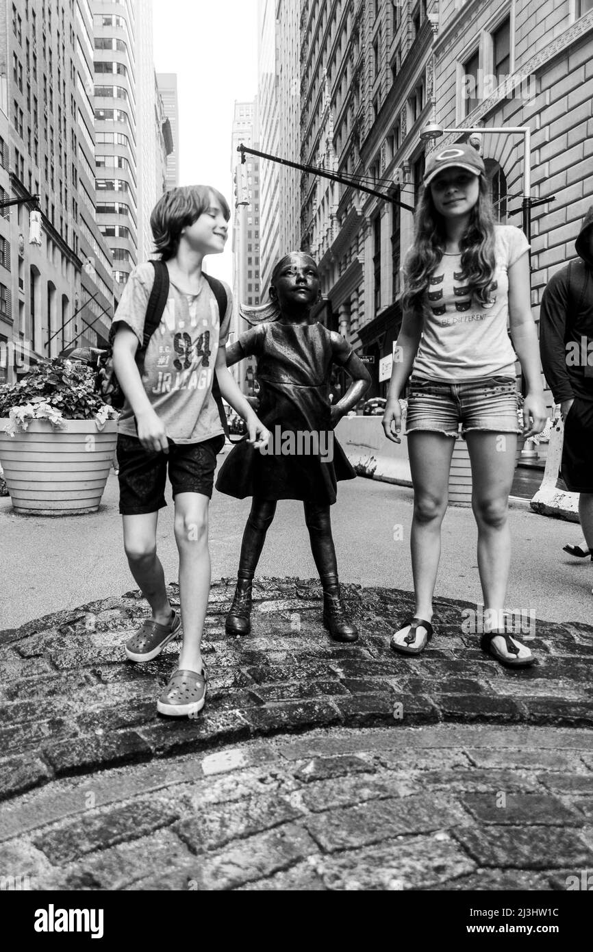 Financial District, New York City, NY, USA, adolescente caucasico di 14 anni e ragazzo adolescente caucasico di 12 anni - entrambi con capelli marroni e stile estivo in piedi accanto alla statua 'Fearless Girl', di Kristen Visbal, su Broad Street di fronte alla Borsa di New York Foto Stock