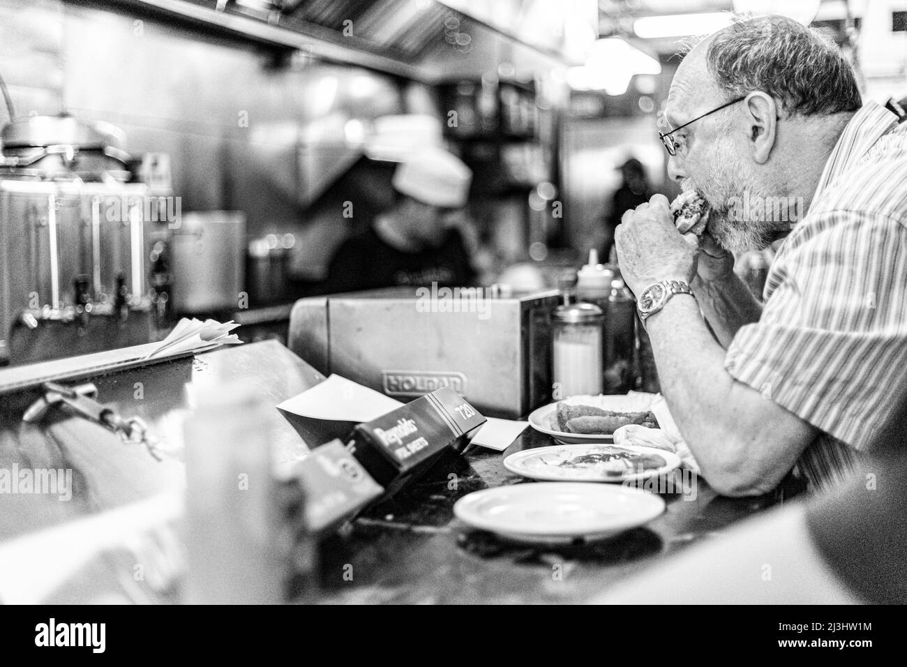 23 Street, New York City, NY, USA, Old Man mangiare un panino nel Sandwich Shop di Eisenberg - una famosa paninoteca classica di New York. E 'aperto dal 1929 nel distretto di Flatiron. Foto Stock