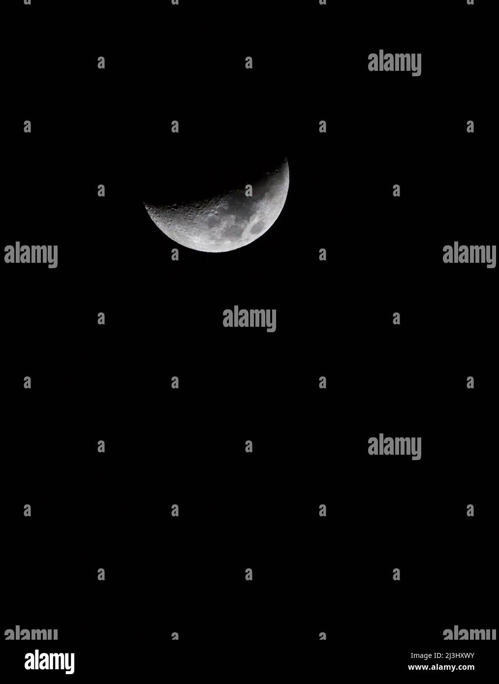 Una composizione verticale di una luna a mezzaluna con spazio di copia in un profondo cielo nero. Foto Stock