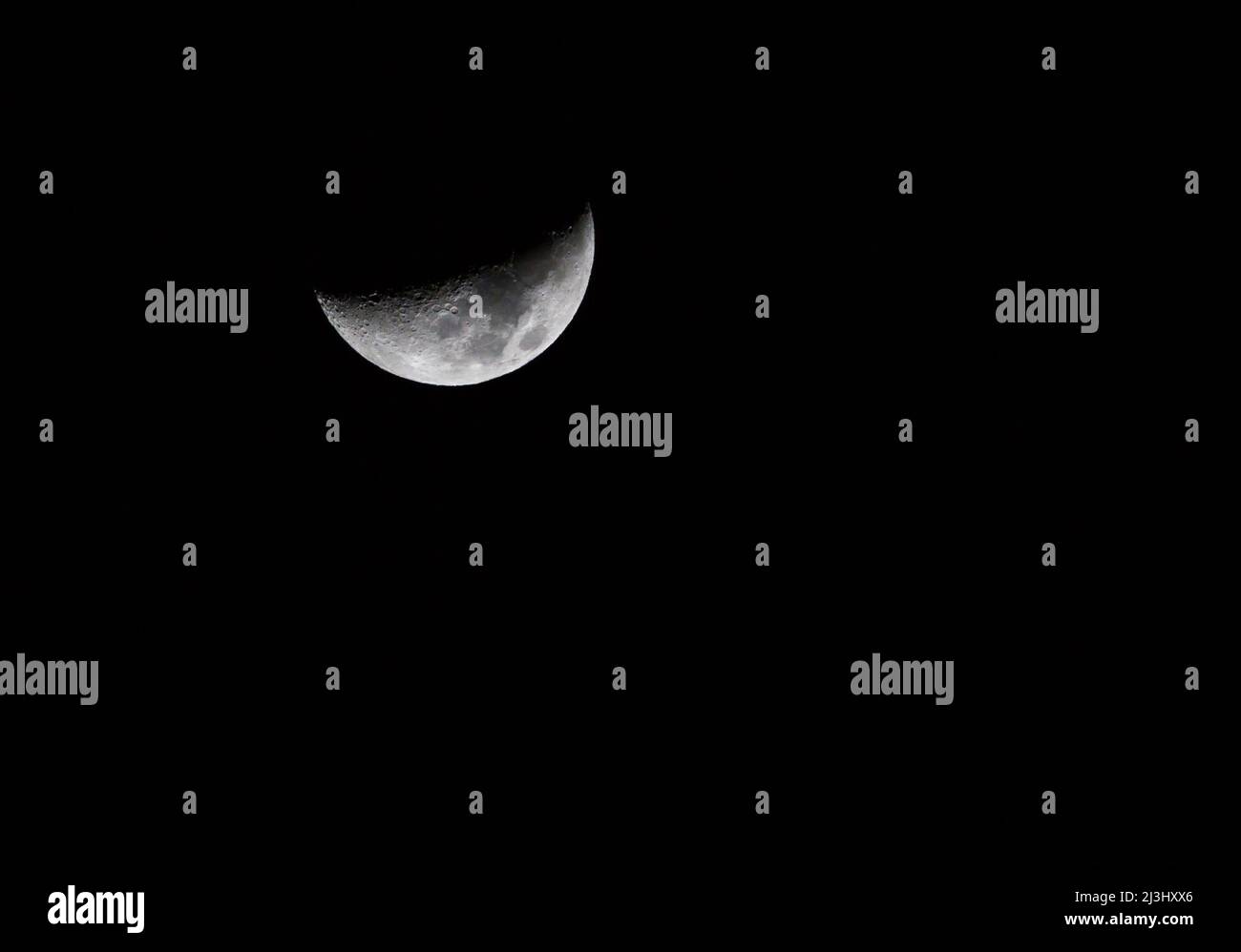 Una composizione orizzontale di una luna a mezzaluna con spazio di copia in un profondo cielo nero. Foto Stock