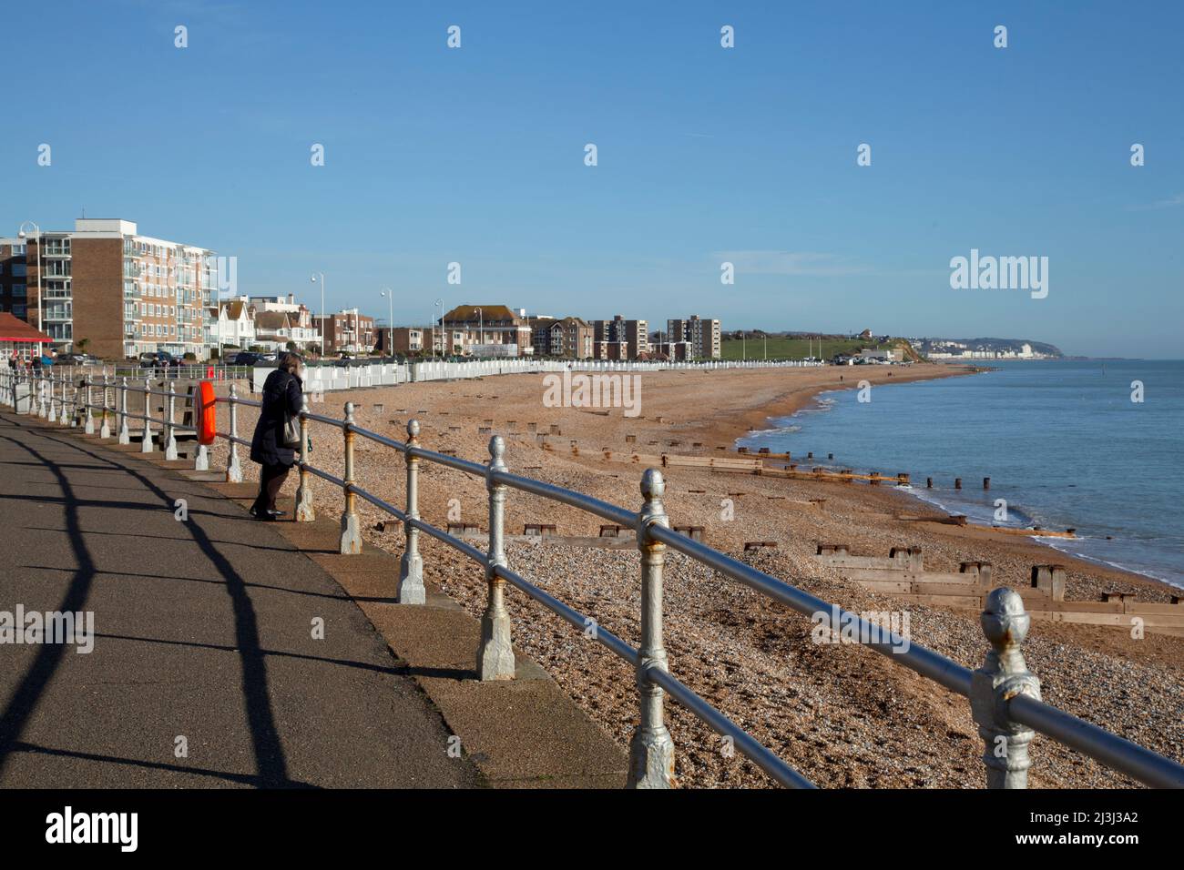 Bexhill-on-Sea, Sussex, la spiaggia dal lungomare con ringhiere e una persona che guarda il mare Foto Stock