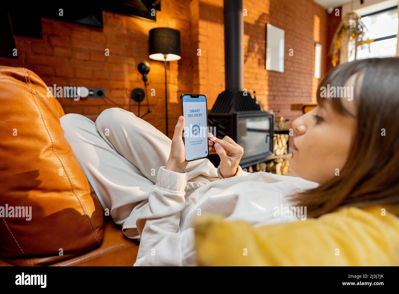 Donna che usa uno smartphone con un'applicazione di consegna in esecuzione a casa Foto Stock