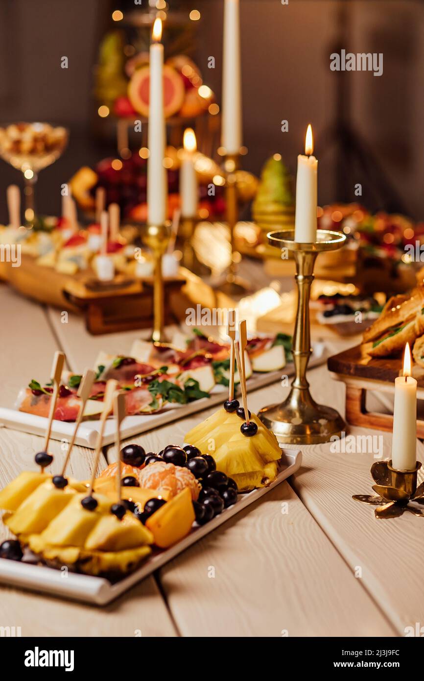 cibo servito al tavolo festivo, piatti di frutta, formaggio, tartine e affettati per il buffet. Catering Foto Stock