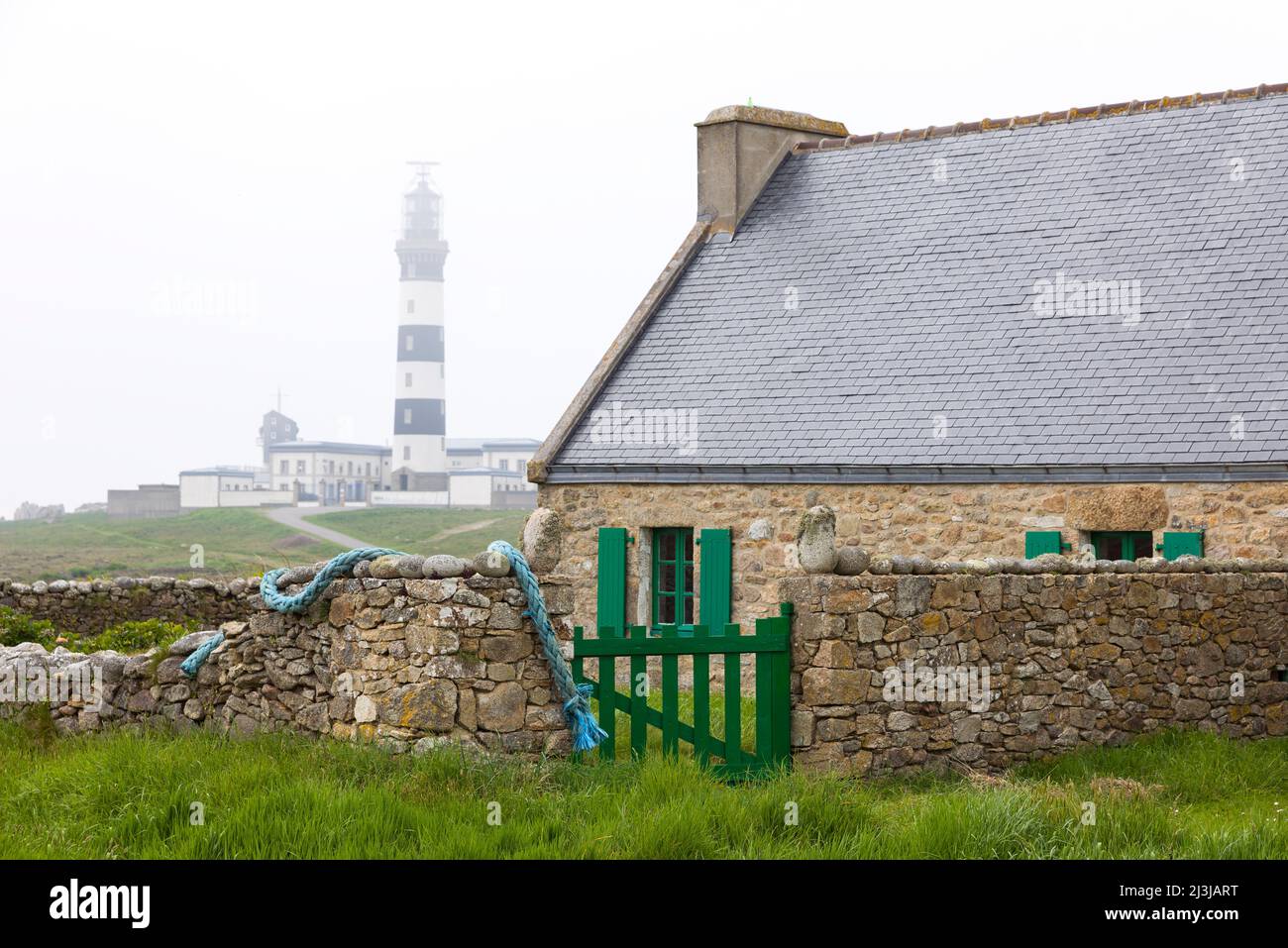 Casa e muro di pietra, il faro di Créac'h sullo sfondo, atmosfera nebbia, ÃŽle d'Ouessant, Francia, Bretagna, Dipartimento del Finistère Foto Stock