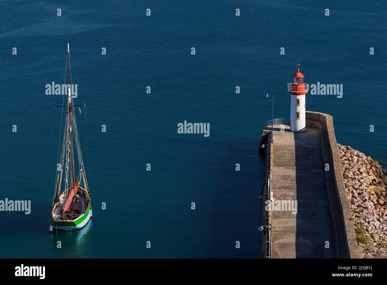 Barca a vela nel porto di Erquy, vista sul molo e il faro, Francia, Bretagna, dipartimento Côtes d'Armor, Côte de Penthièvre Foto Stock