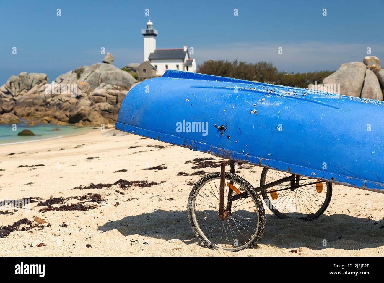 Barca blu con ruote sulla spiaggia di Pointe de Beg Pol, sullo sfondo faro Pontusval, vicino Brignogan-Plage, Francia, Bretagna, dipartimento Finistère Foto Stock