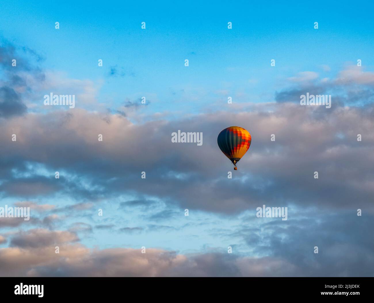 Un pallone ad aria calda che vola attraverso il cielo nuvoloso Foto Stock