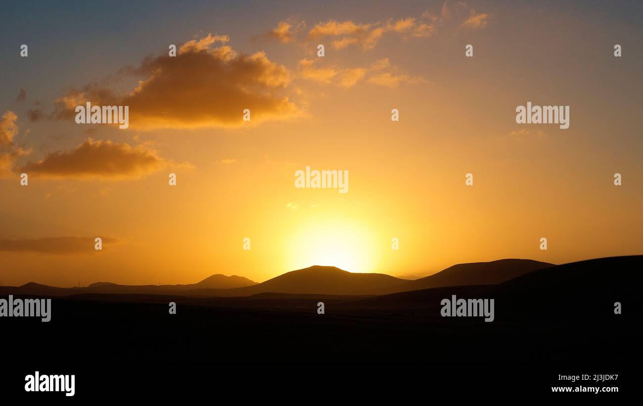 Spagna, Isole Canarie, Fuerteventura, zona delle dune di El Jable, tramonto, dune, cielo azzurro ad arancio, Foto Stock
