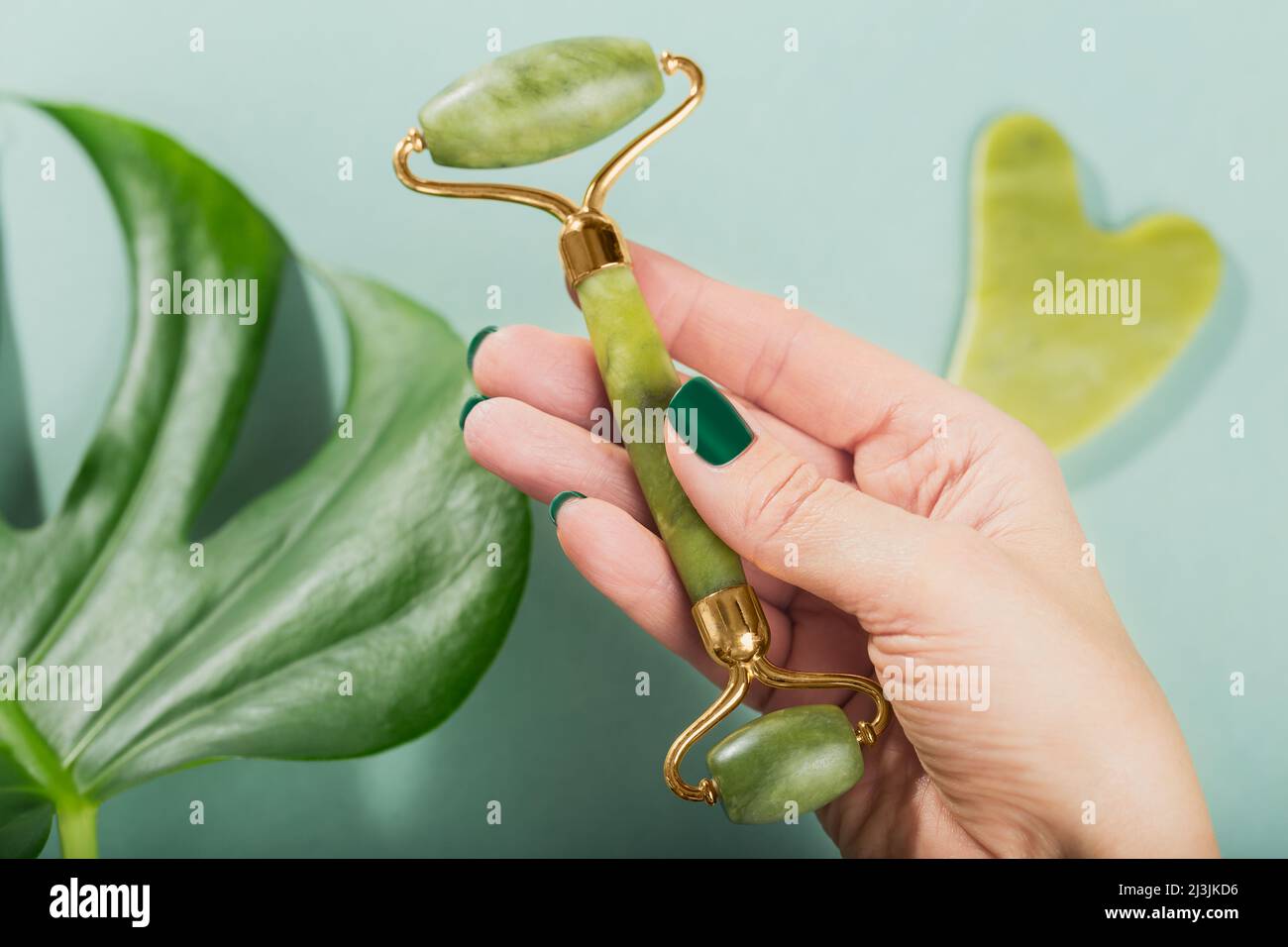 Rullo massaggiante femmina per il viso con due teste di pietra verde Foto Stock