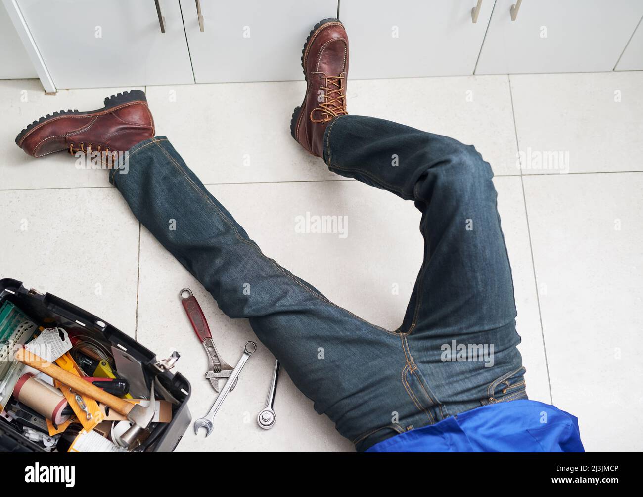 Scendendo ad un certo DIY. Scatto ritagliato di un uomo che effettua riparazioni sul pavimento accanto alla sua cassetta degli attrezzi. Foto Stock