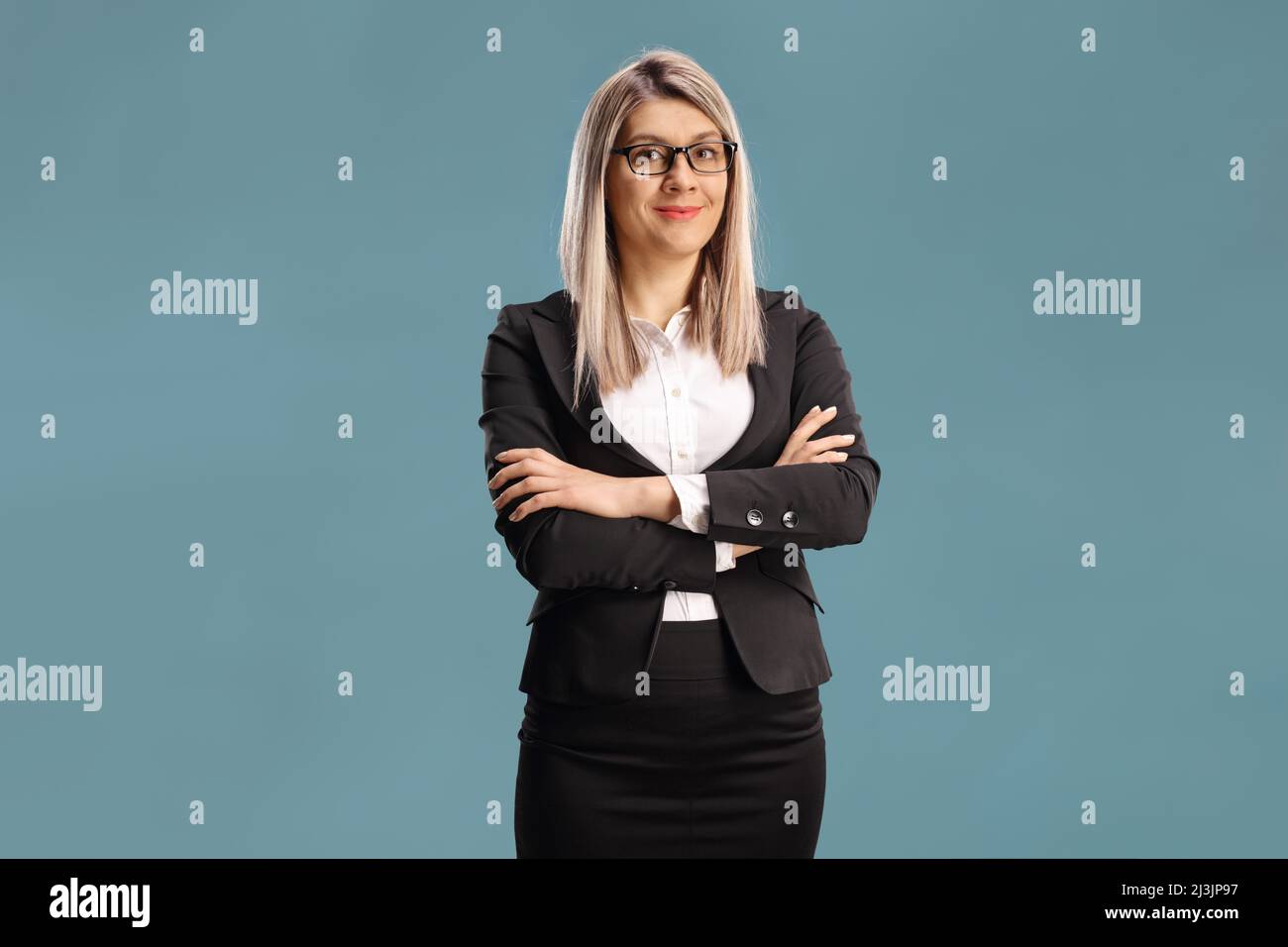 Donna d'affari con occhiali in posa isolato su sfondo blu Foto Stock