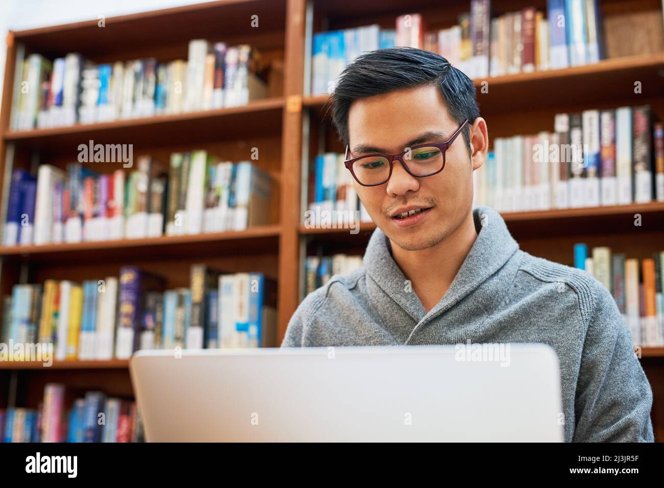 Egli si impegna solo per il successo attraverso il duro lavoro. Scatto di un giovane concentrato impegnato a lavorare sul suo laptop e studiare mentre si siede all'interno di un Foto Stock