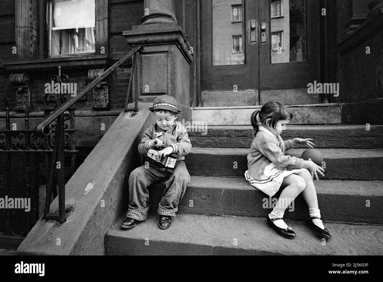 Ragazzo che gioca con il camion giocattolo, ragazza che gioca con la palla sui gradini anteriori dell'edificio dell'appartamento, New York City, New York, USA, Angelo Rizzuto, Anthony Angel Collection, maggio 1961 Foto Stock