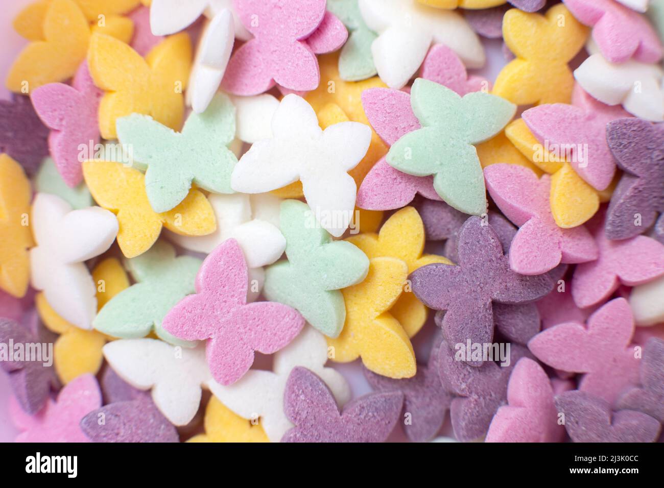 Farfalle colorate, spolverini di pasticceria popolare, fondo solido. Foto Stock