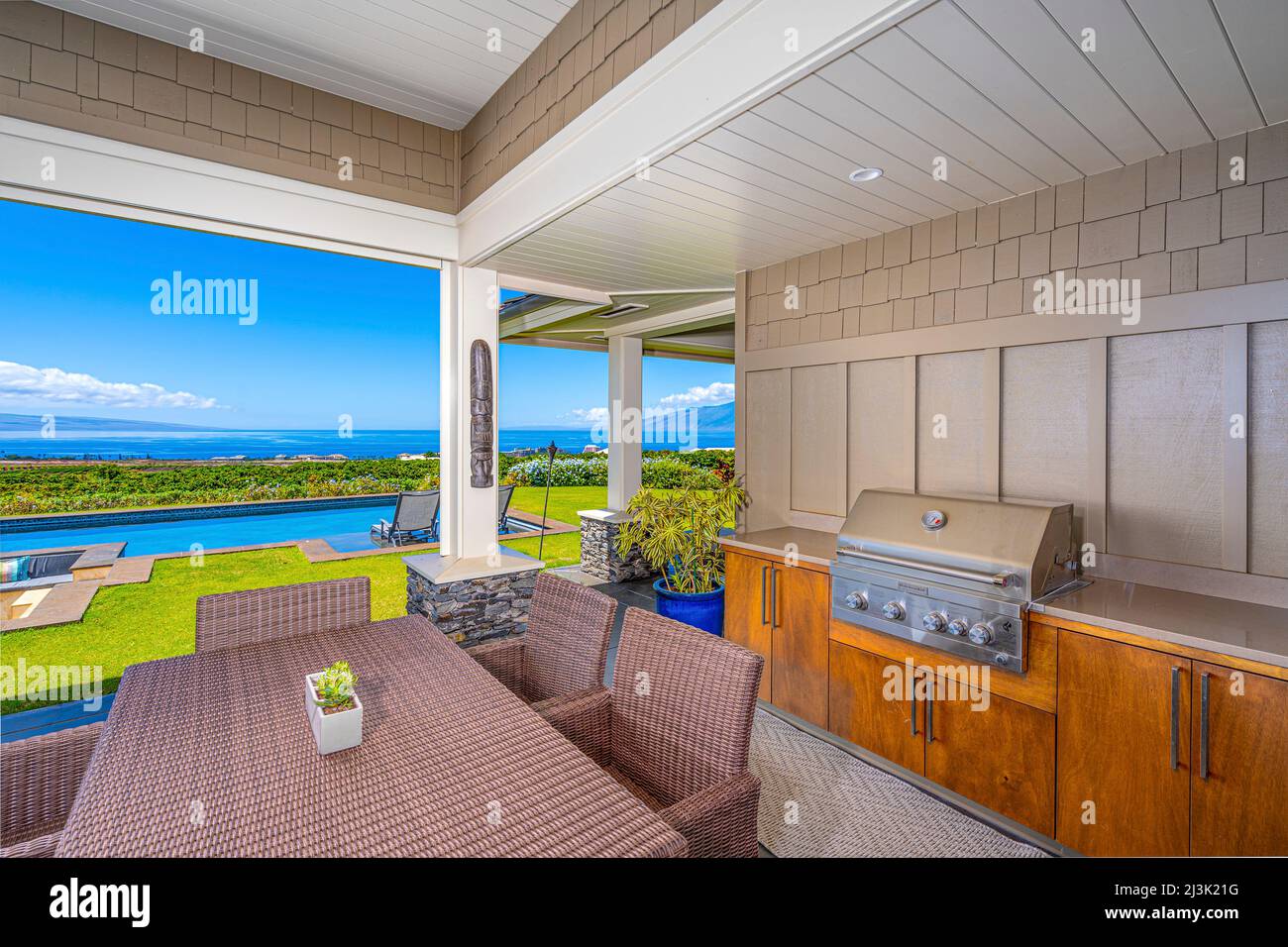 Cucina all'aperto con barbecue e tavolo con sedie su un patio con una piscina nelle vicinanze e una vista sull'oceano Pacifico Foto Stock