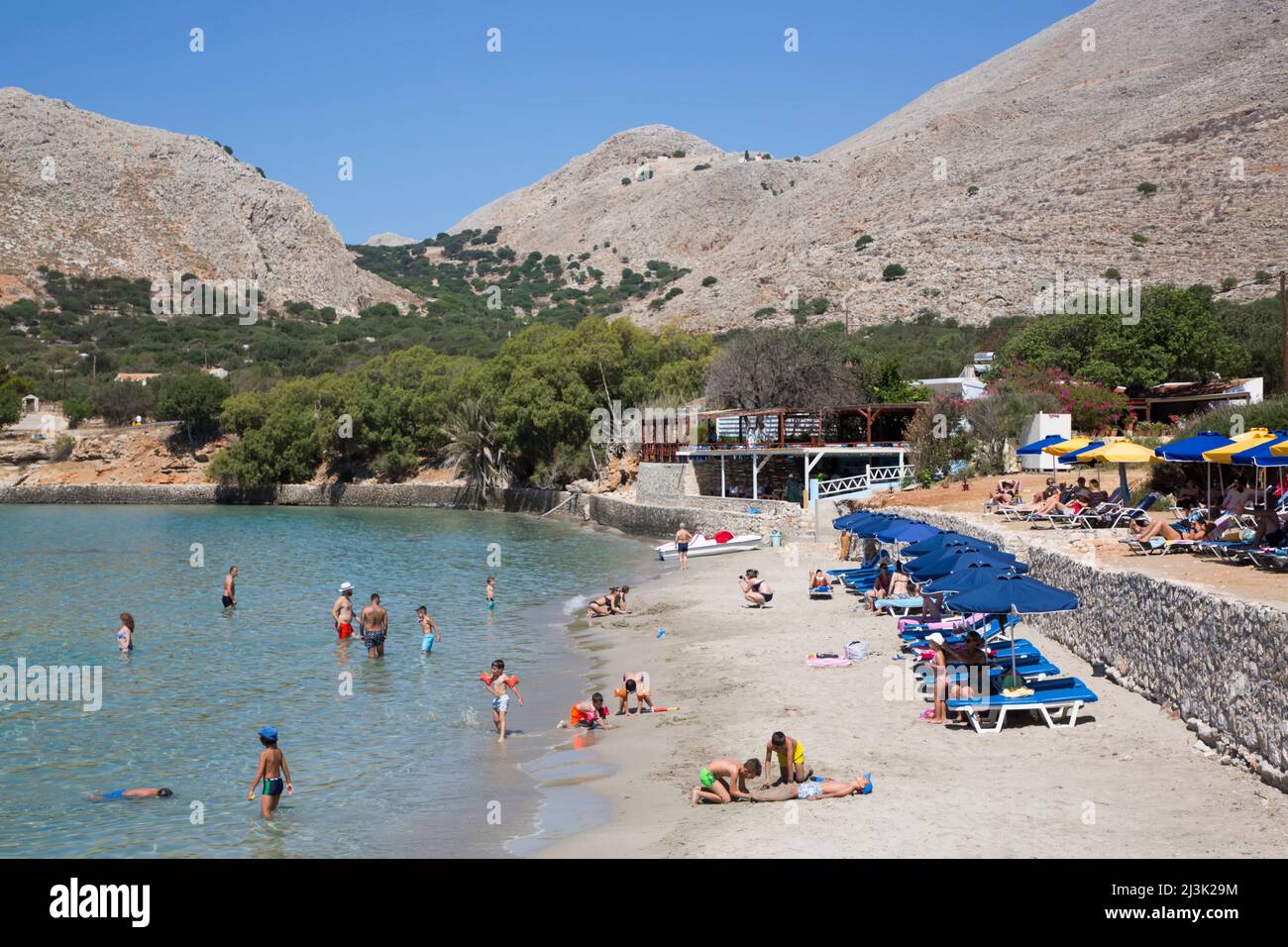 Bagnanti e nuotatori che si godono Pontamos Beach sull'isola di Halki, Grecia; Halki, Dodecaneso, Grecia Foto Stock