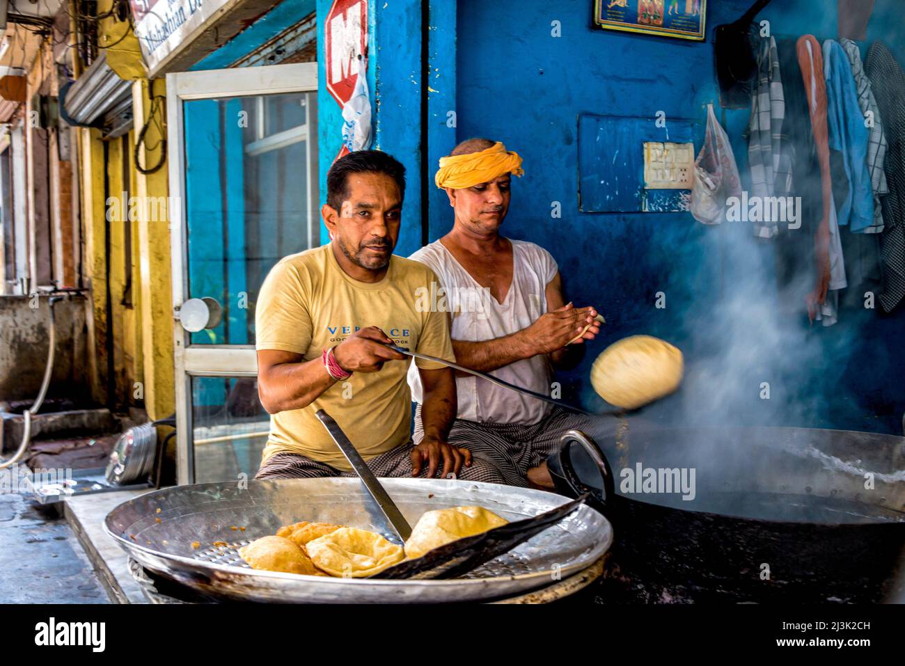 Gli uomini che fanno il cibo indiano tradizionale in una bancarella di strada in India, il pane fritto profondo lanuginoso; Amritsar, Punjab, India Foto Stock