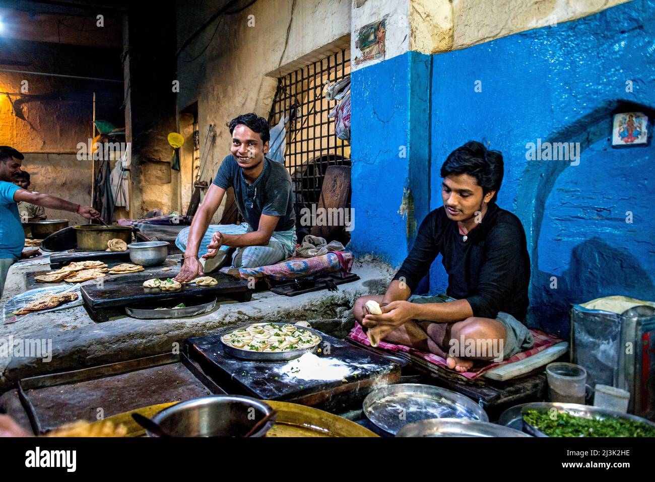 Giovani uomini che lavorano in una cucina commerciale preparando cibo sotto le luci in India; Amritsar, Punjab, India Foto Stock