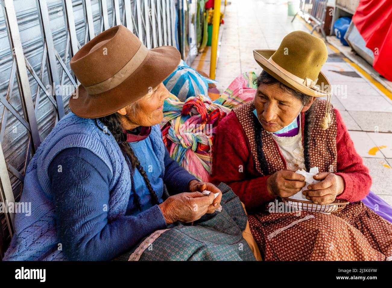 Due donne anziane seduti a mangiare uno spuntino al mercato di San Camilo, Arequipa, Regione di Arequipa, Perù. Foto Stock