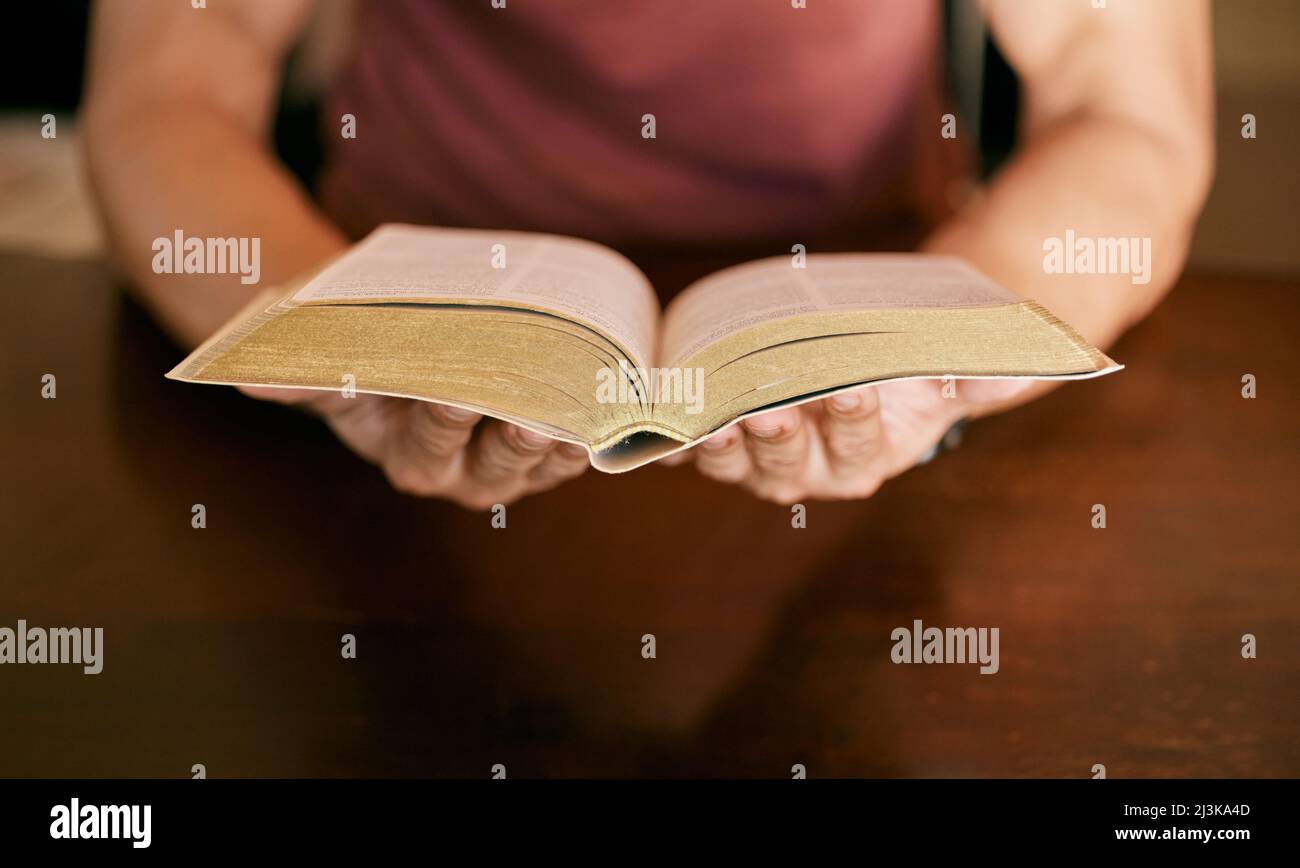 La mia bibbia è uno dei miei beni più importanti. Colpo di un giovane seduto tenendo una bibbia nelle sue mani. Foto Stock