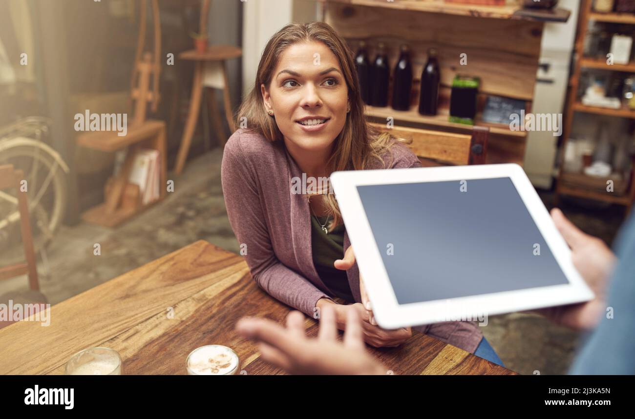 Ascoltare le specialità del giorno. Scatto di una giovane donna che fa il suo ordine con un cameriere utilizzando un tablet digitale. Foto Stock