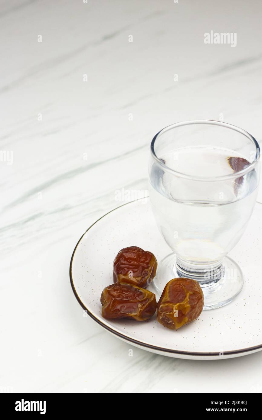 Kurma dan Air Putih, datteri di Sukkari e acqua su sfondo bianco marmo. Concetto di breakfasting nel mese del Ramadan. Modello islamico per lo sfondo del testo. Foto Stock