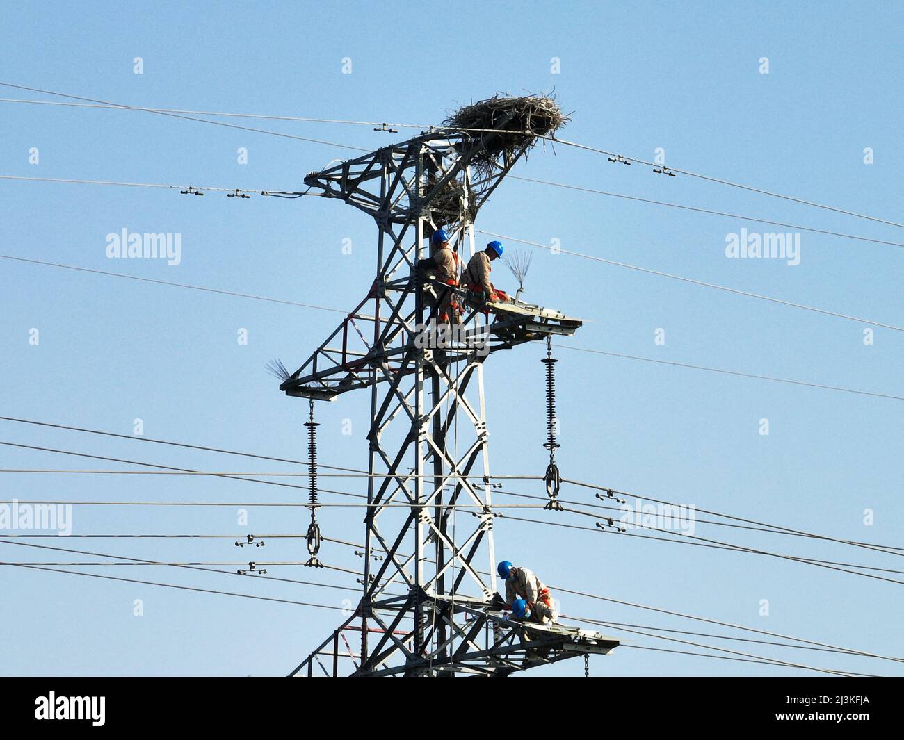 SUQIAN, CINA - 8 APRILE 2022 - Un lavoratore di alimentazione installa uno scudo per uccelli su una torre di trasmissione per impedire ai nidi di uccelli di cadere rami. In S. Foto Stock