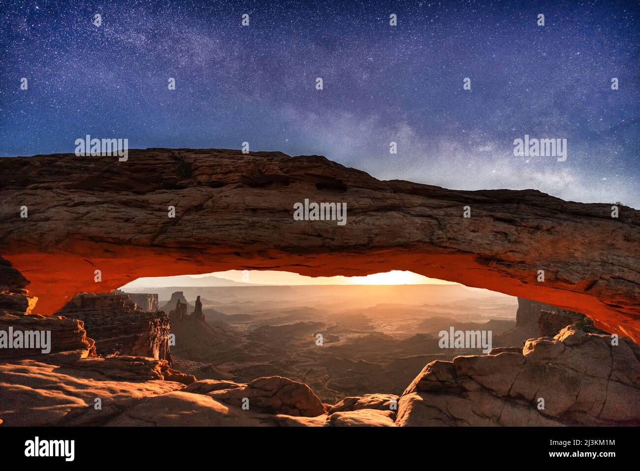Una rara immagine della via lattiginosa e della luna che si innalza per illuminare il paesaggio desertico sotto Mesa Arch, Parco Nazionale Canyonlands Foto Stock