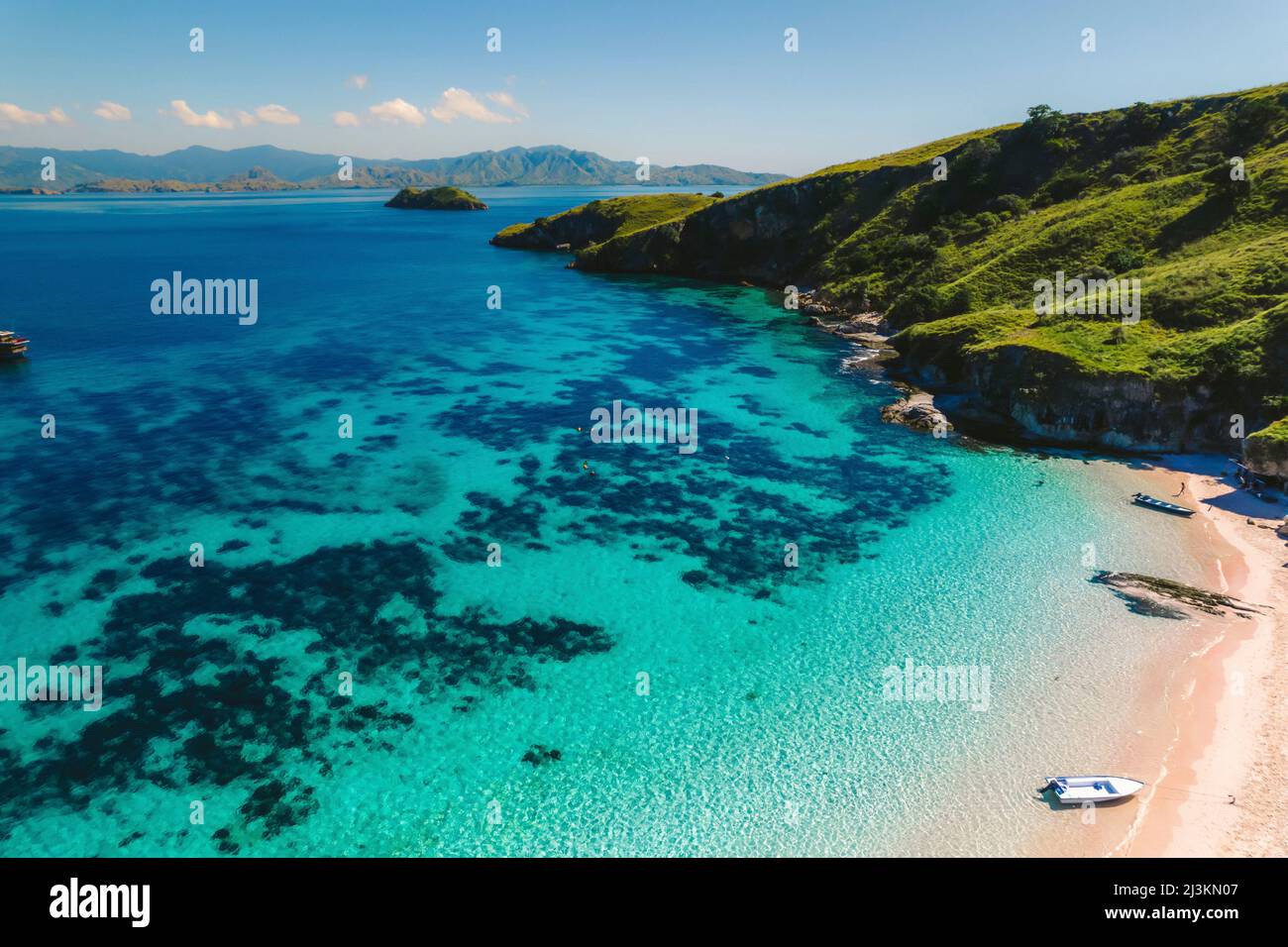 Vista aerea un motoscafi sulla riva di una spiaggia di sabbia rosa e le persone che si godono il mare lungo la riva dell'isola di Padar a Komodo Natio... Foto Stock