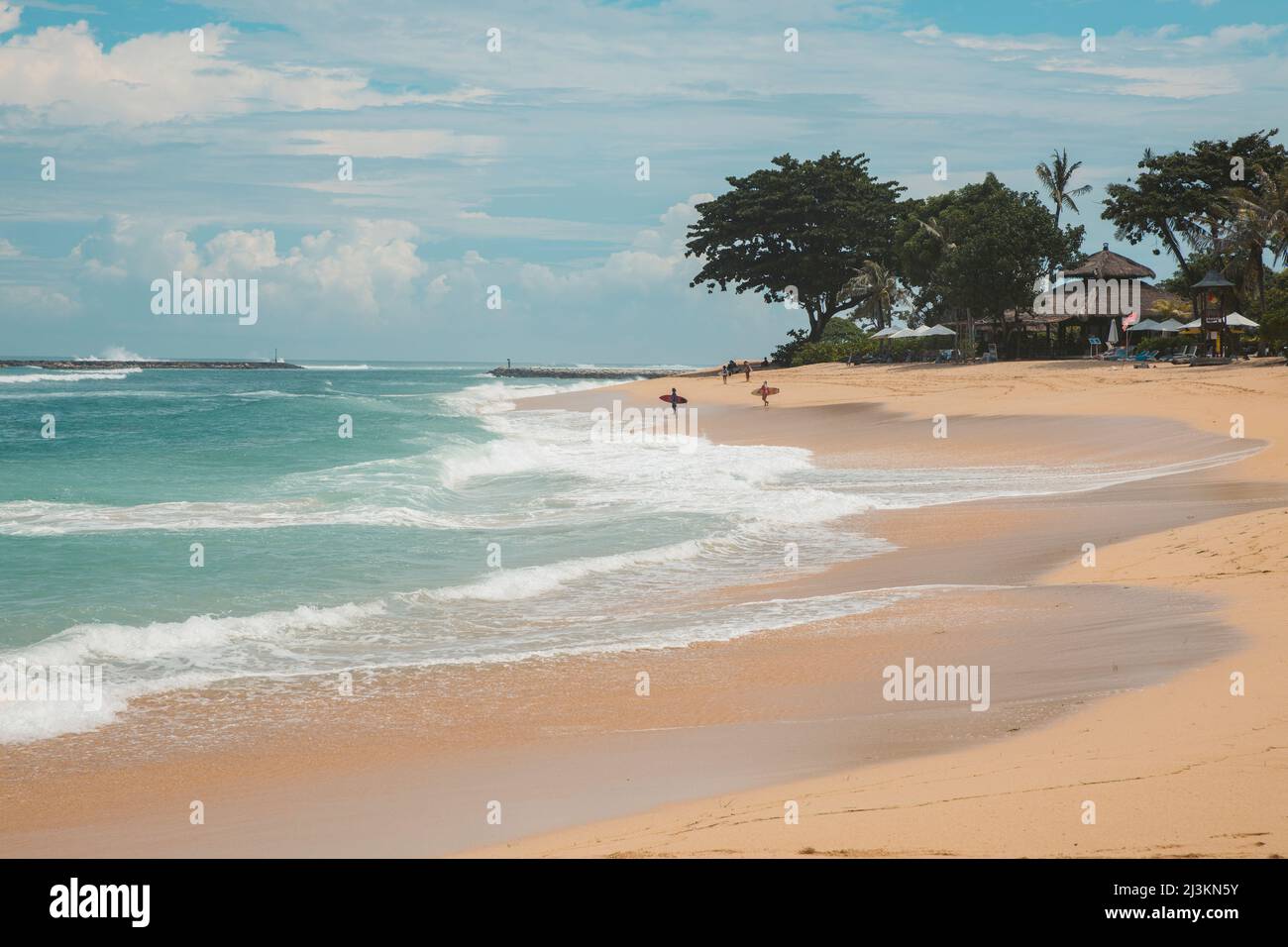 Surfers in piedi sulla spiaggia al bordo dell'acqua in attesa delle onde a Geger Beach nella zona di Nusa Dua resort Foto Stock
