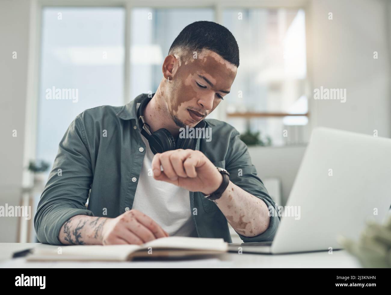 Non lasciate che la paura di perdere vi fermi. Scatto di un giovane uomo d'affari che controlla il suo orologio in un ufficio moderno. Foto Stock
