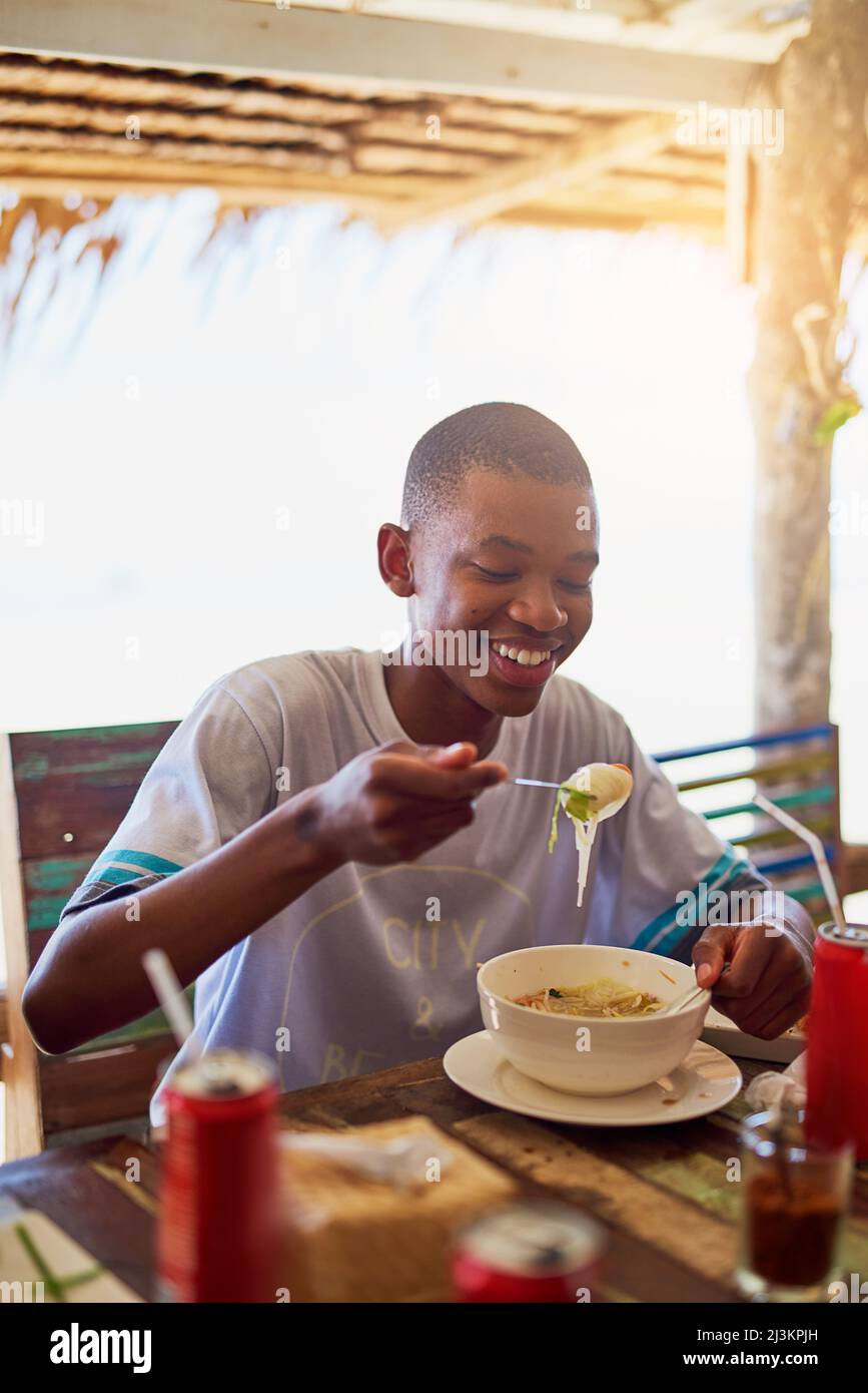Provate la cucina locale. Shot di un giovane che mangia una ciotola di tagliatelle in un ristorante in Thailandia. Foto Stock