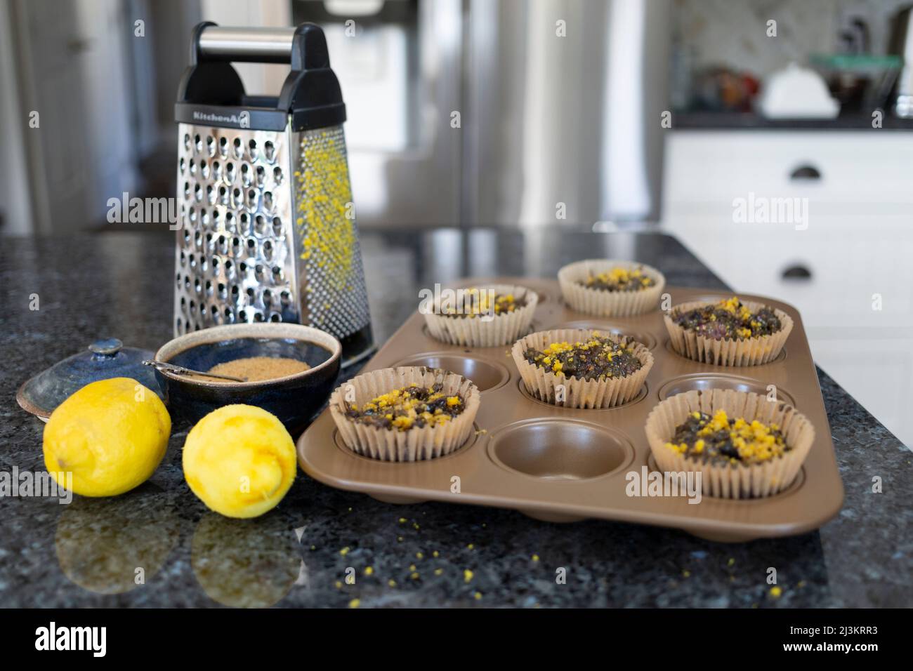 Muffin da forno con scorza di limone e limoni freschi con grattugia sul banco della cucina; Kelowna, British Columbia, Canada Foto Stock