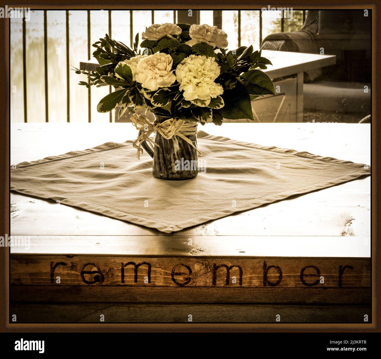 Grafica incorniciata in tonalità seppia che mostra una disposizione di fiori in una casa su un tavolo da caffè in legno con la parola 'membro' incisa sul lato Foto Stock