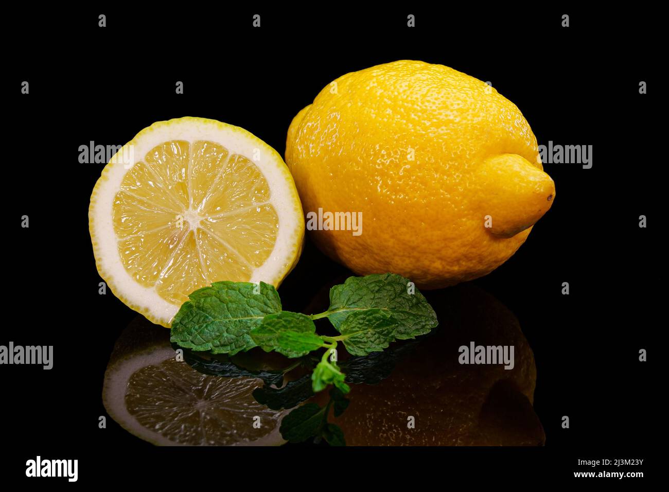 Limone giallo con foglie di menta su fondo nero. Limone fresco, perfetto, biologico e vivace in foglia di menta Foto Stock