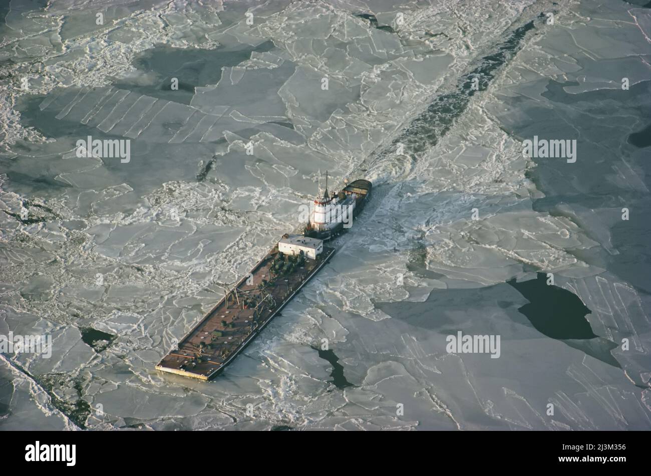 Tugboat spinta chiatta attraverso ghiaccio invernale sulla Chesapeake Bay.; CHESAPEAKE BAY, MARYLAND. Foto Stock