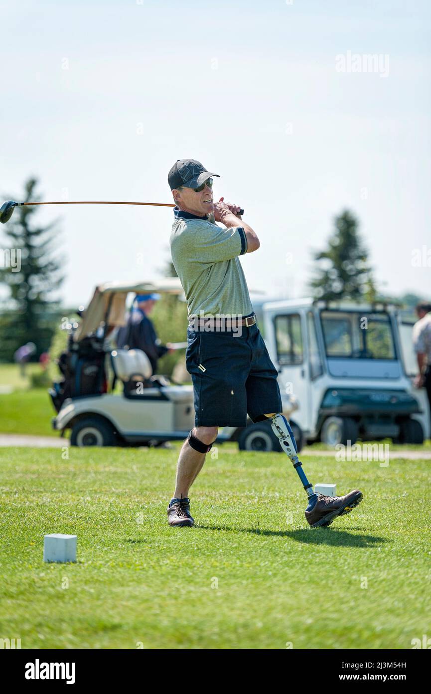Amputee con protesi di gamba che guida la palla sul campo da golf; Okotoks, Alberta, Canada Foto Stock
