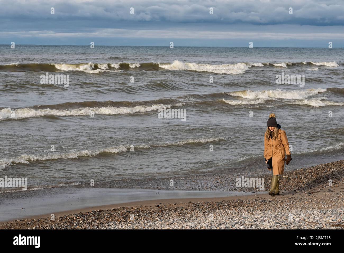 Donna che cammina lungo la riva del lago Huron in Ontario; Grand Bend, Ontario, Canada Foto Stock