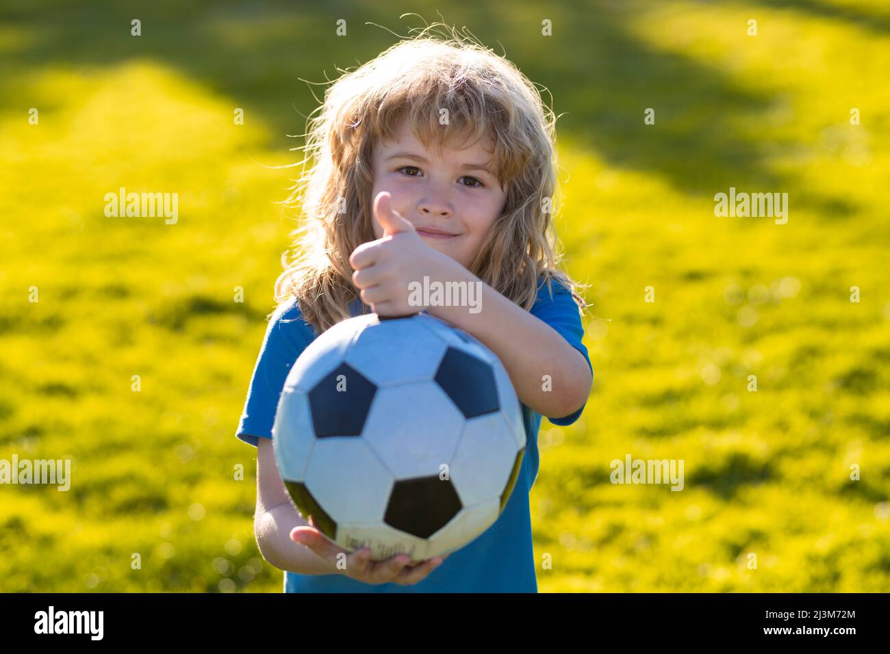 Bambino che gioca a calcio, bambino felice che gode di sport gioco di calcio,  attività per bambini, piccolo giocatore di calcio. Il calcio sportivo  attivo del capretto mostra i pollici in su