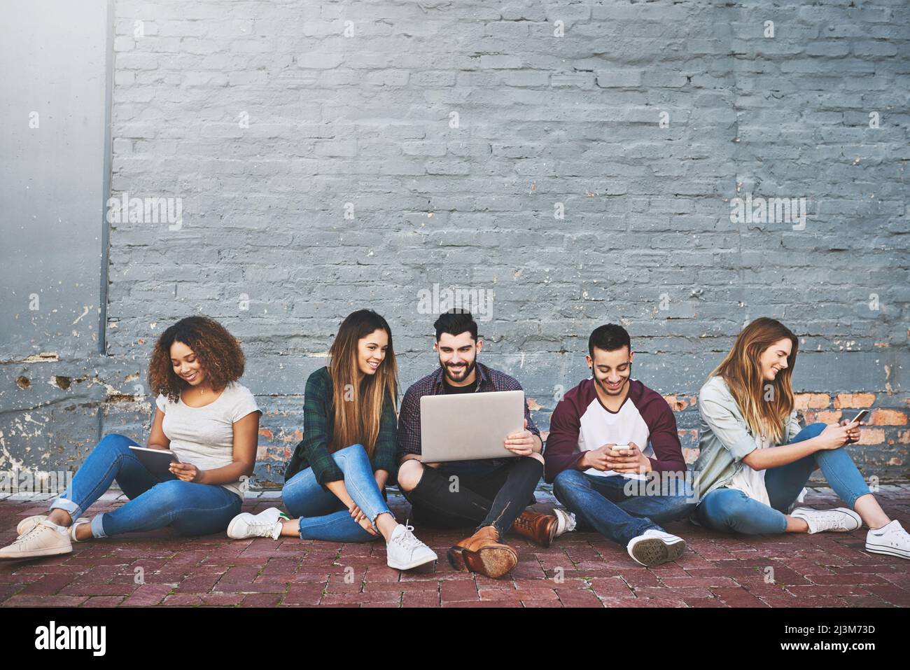 Connessione in un'era connessa. Foto di un gruppo di giovani amici che utilizzano i loro dispositivi wireless all'aperto. Foto Stock