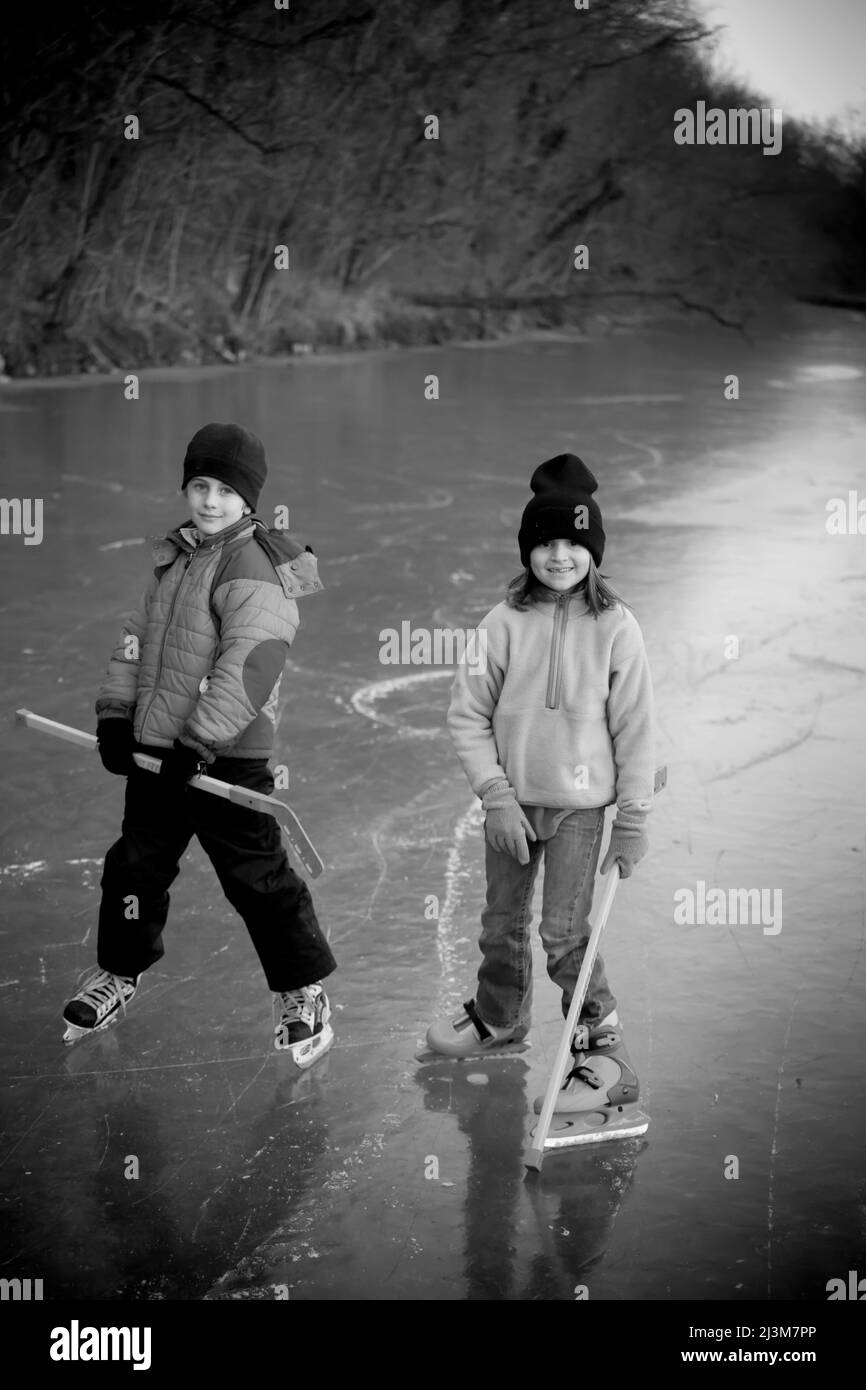 Ragazzo e ragazza di otto anni si prendono una pausa dal stagno hockey.; C&o Canal, Bethesda, Maryland. Foto Stock