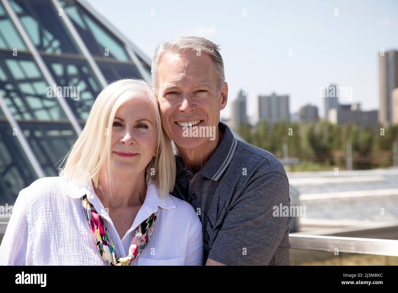 Ritratto all'aperto di una coppia matura con uno skyline della città e l'architettura in background urbano; Edmonton, Alberta, Canada Foto Stock