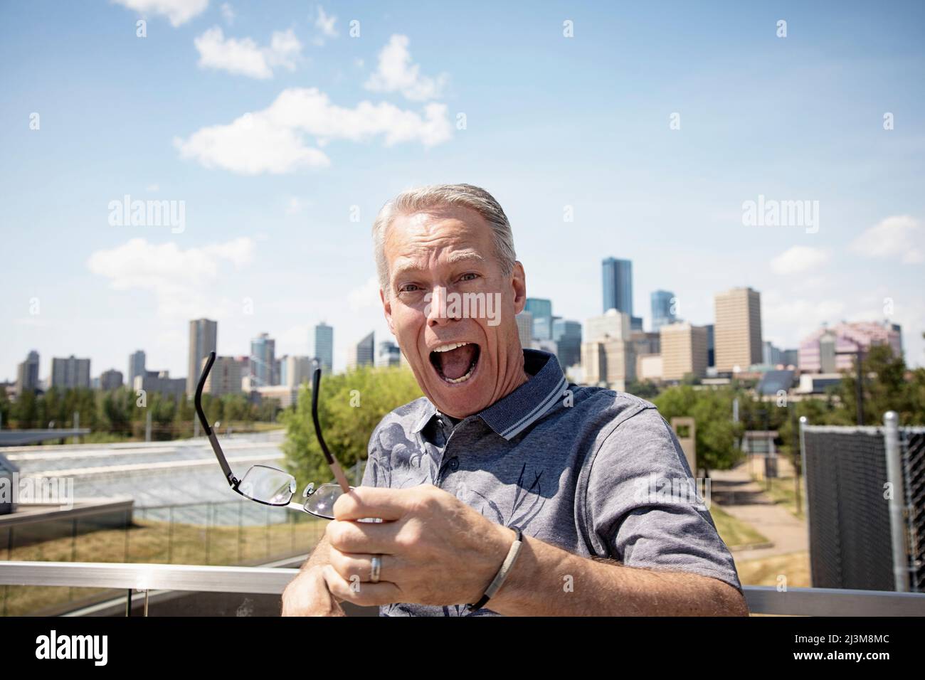 L'uomo anziano in piedi all'aperto tiene i suoi occhiali in mano per guardare la fotocamera con un'espressione sorpresa sul suo volto; Edmonton, Alberta, Canada Foto Stock L'uomo anziano in piedi all'aperto tiene i suoi occhiali in mano per guardare la fotocamera con un'espressione sorpresa sul suo volto; Edmonton, Alberta, Canada Foto Stock