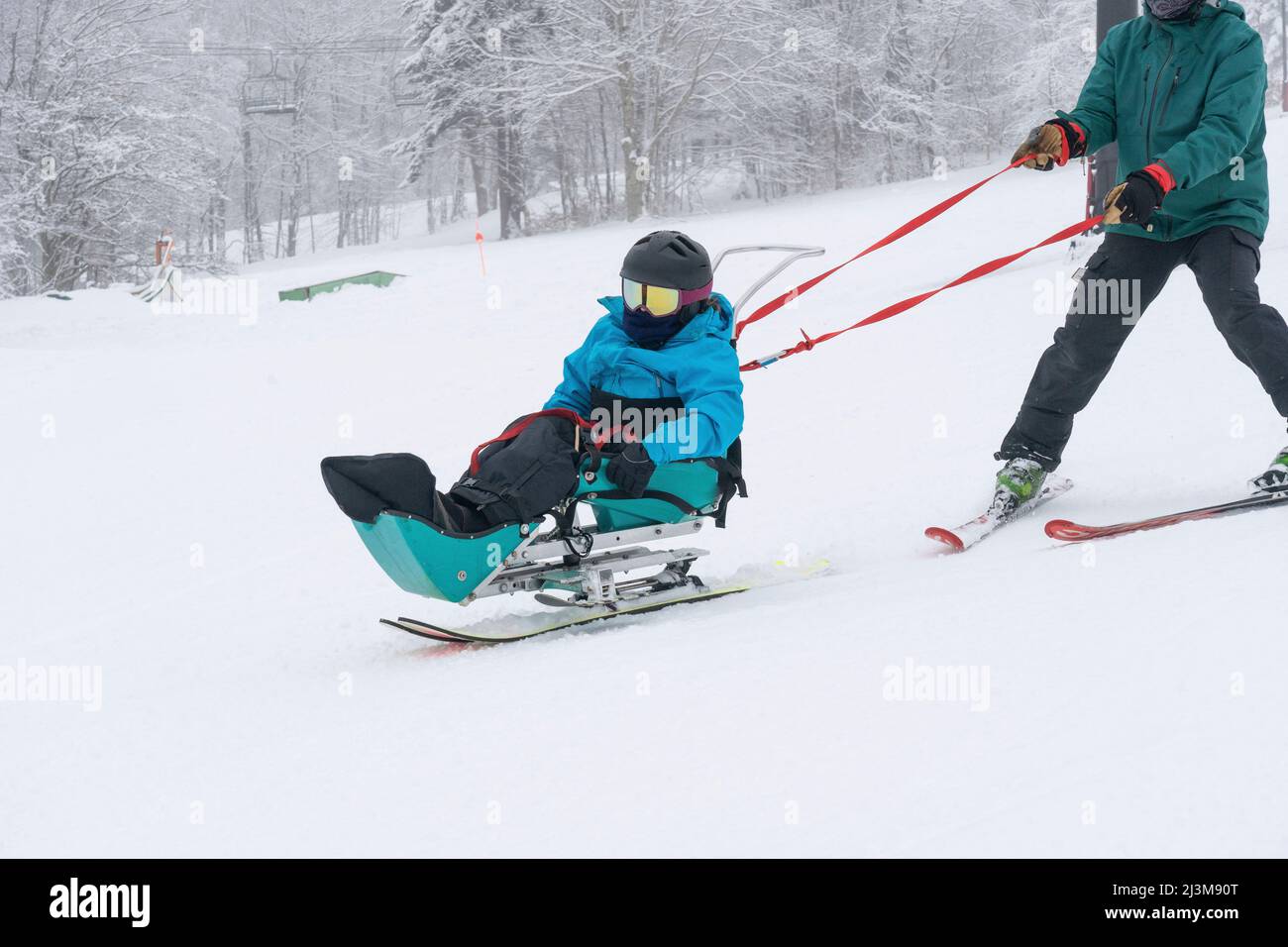Sci adattivo per una ragazza con Ullrich muscoloso distrofia congenita, in una stazione sciistica con istruttore Foto Stock