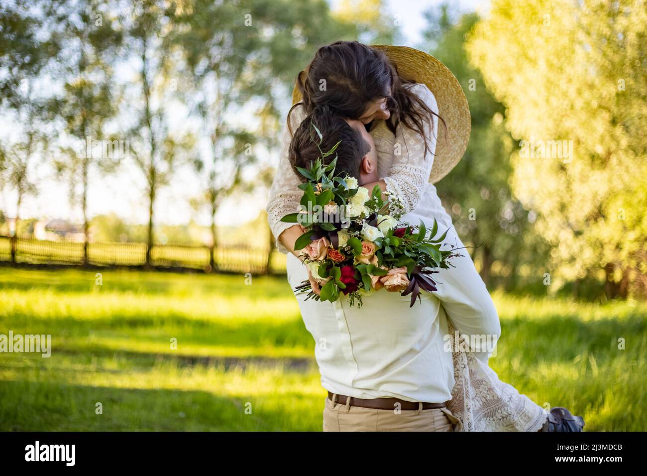 Elegante sposa felice, presa dello sposo in mano e ballare. Lo sposo si alzò e gira sposa. Baciare gli sposi novelli. Sullo sfondo sulla natura in co Foto Stock