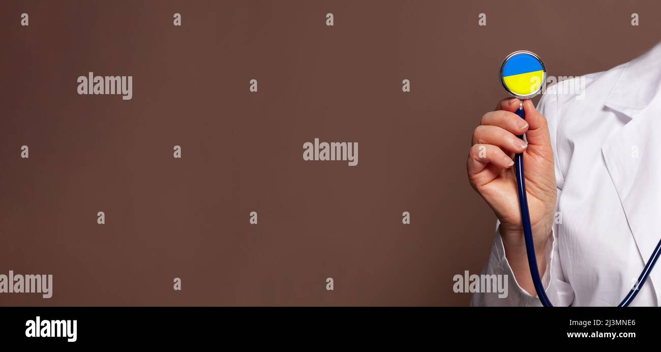 Stetoscopio con mano del medico con il colore della bandiera Ucraina su sfondo marrone. Medicina di concetto in Ucraina Foto Stock